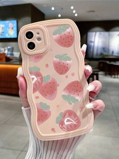 a woman holding up a phone case with strawberries on it