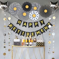 a party with black and gold decorations, silver balloons and streamers on the wall