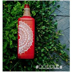 a red bottle sitting on top of a lush green plant filled with leaves and flowers