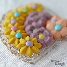 three different colored cookies in a glass dish on a white tablecloth with flowers and polka dots