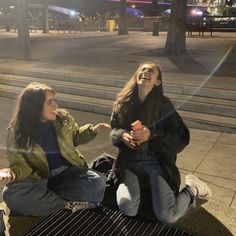 two women sitting on a bench talking and laughing