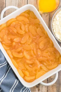 an apple cobbler with oatmeal and orange juice in the background on a wooden table