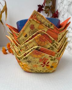 a stack of small bowls sitting on top of a white table next to orange flowers