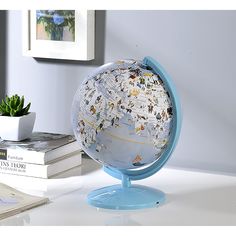 a globe on a table next to books and a potted plant