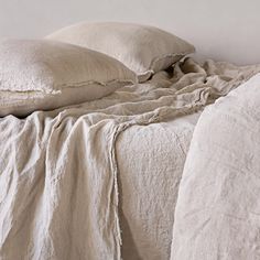 an unmade bed with white linens and pillows