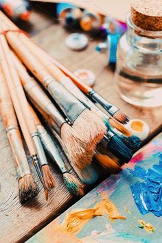 an assortment of paintbrushes and brushes on a wooden table