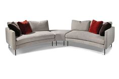 a curved couch with red pillows on it