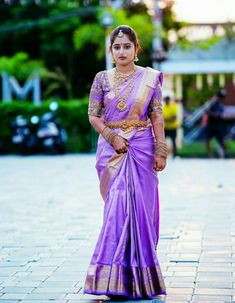 a woman in a purple sari is walking down the street with her hand on her hip