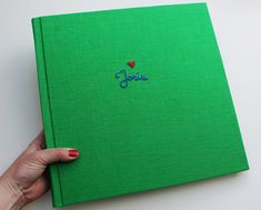 a hand holding a green book with the word love embroidered on it