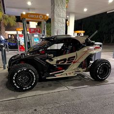 a white and black car parked at a gas station