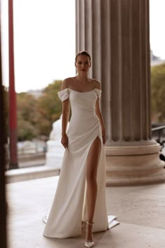 a woman in a white dress is posing for the camera with her leg slited