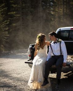 a bride and groom sitting on the back of a pickup truck