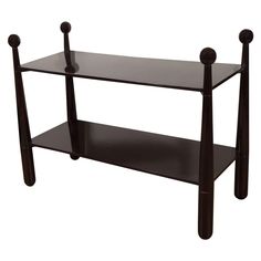 a black shelf with two legs and three balls on the top, against a white background