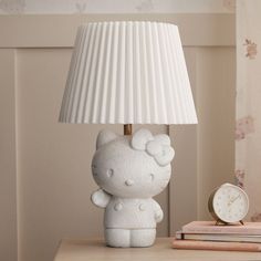 a hello kitty lamp sitting on top of a table next to a book and clock