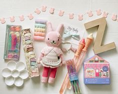 an assortment of toys and crafting supplies laid out on a table with bunting