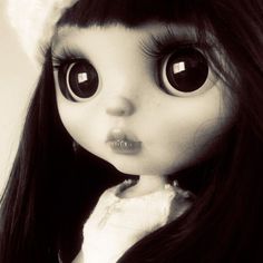 a doll with long black hair and big eyes wearing a white hat on top of it's head