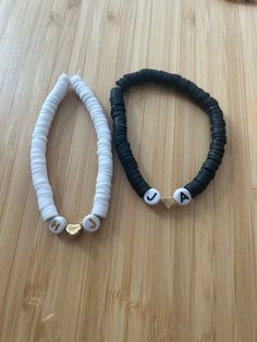 two black and white bracelets sitting on top of a wooden table