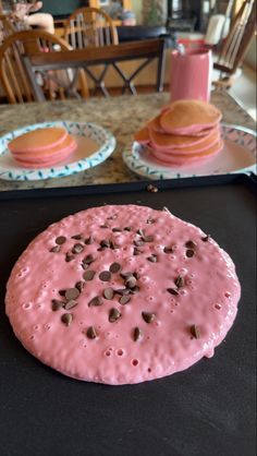 pink frosted doughnut with chocolate chips on it sitting on top of a table