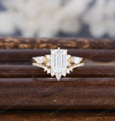 an emerald cut diamond ring sitting on top of a wooden stand