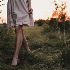 a woman in a dress walking through tall grass