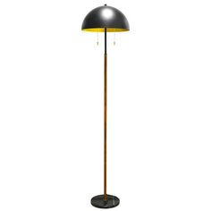 a floor lamp with a black shade on top and a yellow light at the base