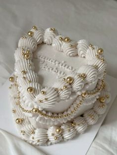 a white and gold beaded heart shaped brooch on top of a piece of paper