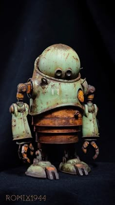 an old rusty robot sitting on top of a black surface