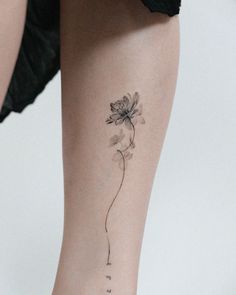 a woman's leg with a single flower tattoo on the left side of her calf