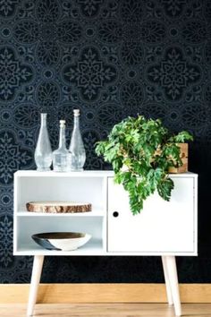 a plant is sitting on top of a white cabinet in front of a black wall