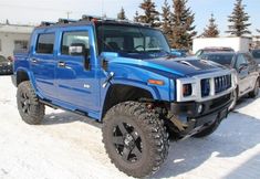 a blue hummer truck parked in the snow