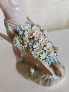 a figurine with flowers on top of it's head and foot in the shape of a shoe