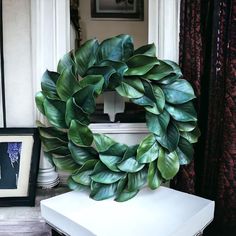 a large green wreath sitting on top of a white table next to a framed photo