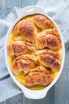 a casserole dish with ham and cheese in it on a blue napkin next to a fork