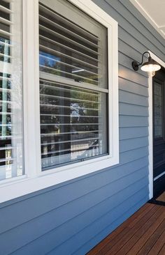 a blue house with white shutters on the front door and wooden decking area