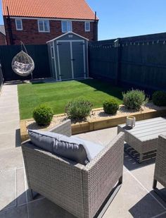 an outdoor patio area with chairs, tables and plants on the lawn in front of a house