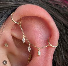 a close up of a person's ear with gold chains