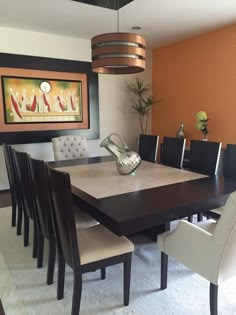 a dining room table and chairs with an orange wall in the background