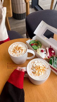 two cups of hot chocolate with marshmallows and whipped cream in them on a table