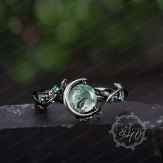 a ring with an image of a woman's face and green crystals on it