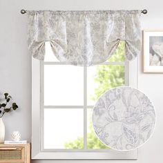 the window is decorated with white and gray curtains, which are hung above a wooden dresser