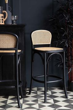 two wicker bar stools sitting next to each other on a checkered floor