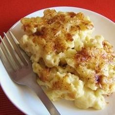 a white plate topped with macaroni and cheese next to a knife and fork