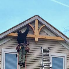 a man standing on top of a ladder in front of a house with a cross