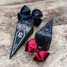 two black and red origami pieces with bows on them sitting on a wooden surface