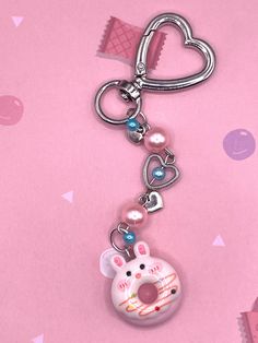 a keychain with a heart shaped object hanging from it's side on a pink background