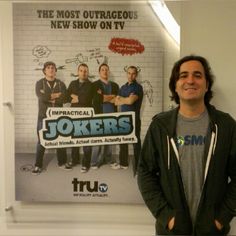 a man standing in front of a poster with the words impracial jokers on it