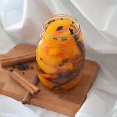 a glass jar filled with liquid sitting on top of a wooden cutting board next to cinnamon sticks