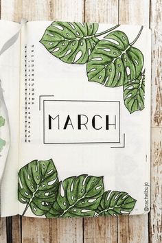 an open book with green leaves on it and the word march written in black ink