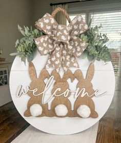 a welcome sign with two bunnies and greenery in the shape of an easter bunny