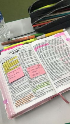 an open bible with sticky notes attached to the pages and colored pencils next to it